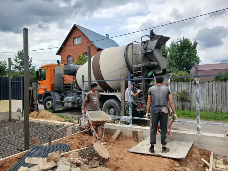 Рабочие принимают бетон из миксера на частной стройке