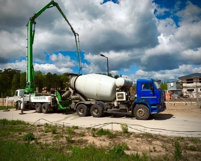 Зелёный автобетононасос в работе на объекте