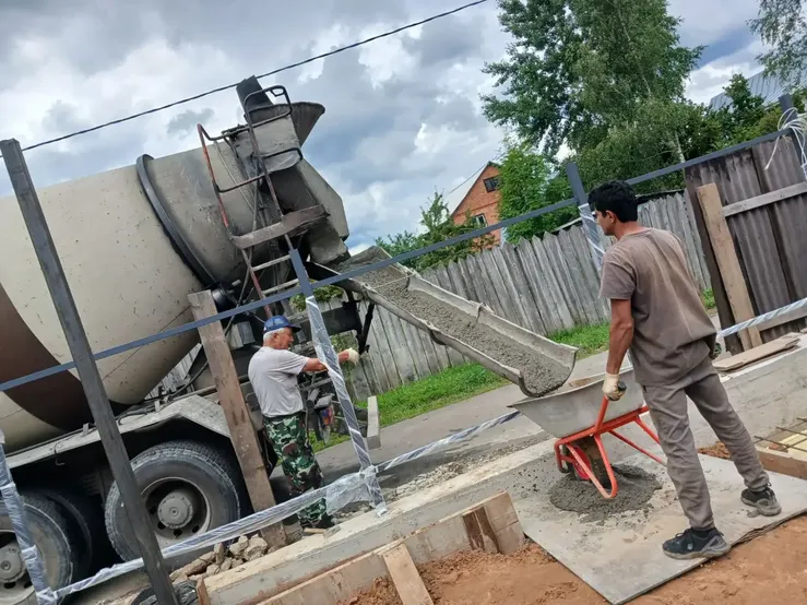 Рабочий принимает бетон из миксера на частной стройке